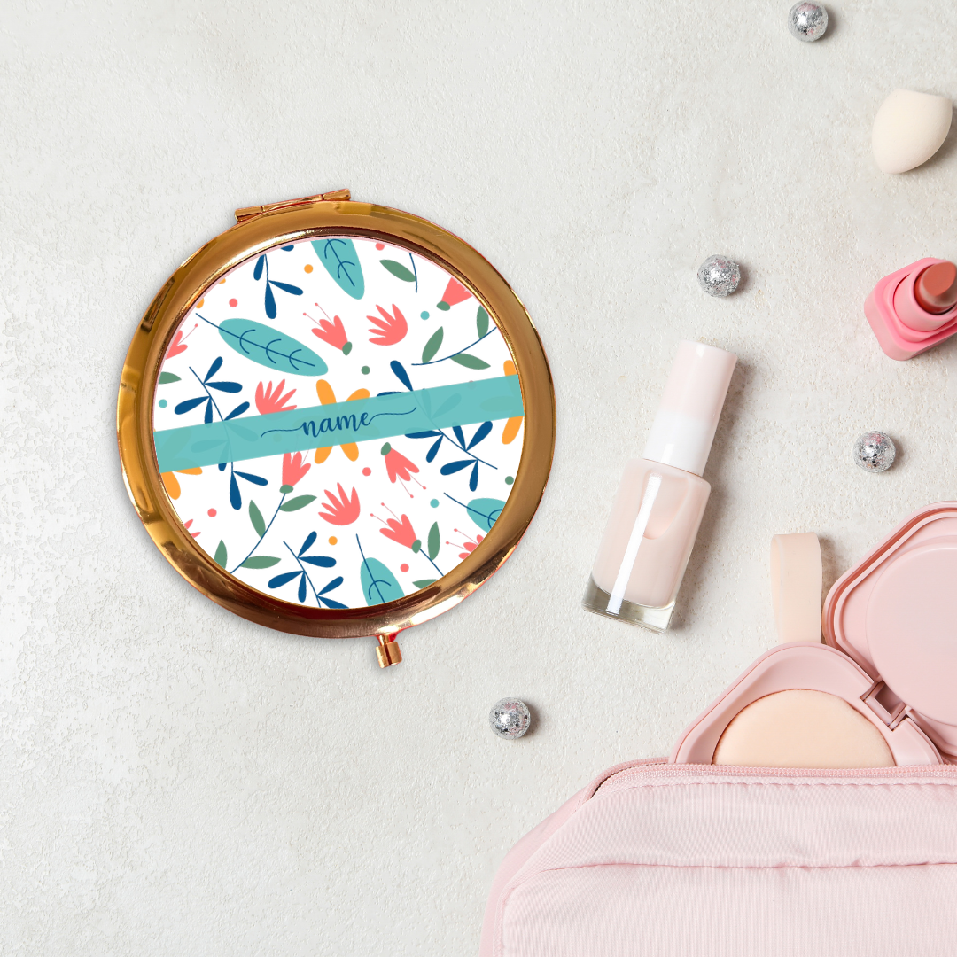 Round floral-patterned compact mirror with makeup items on a light background
