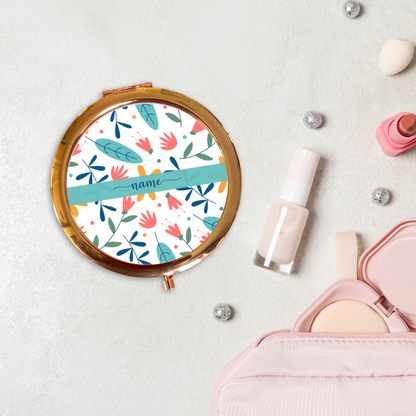Round floral-patterned compact mirror with makeup items on a light background